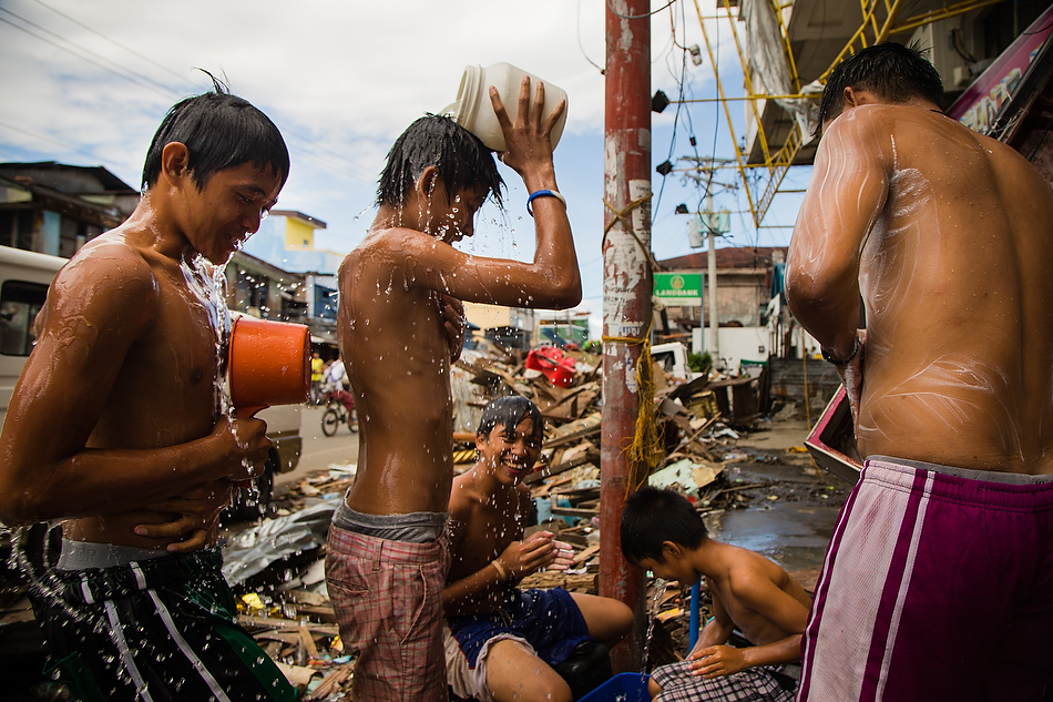 Boys shower and play amongst a street clogged by debris from Typhoon Haiyan in Tacloban City, Leyte province, Philippines on Monday, Nov. 19, 2013. Photo by Erik M. Lunsford/LCMS