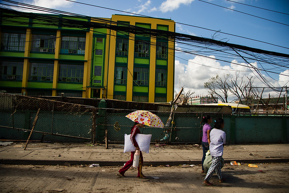 Tacloban City residents carry their belongings along the road in the Philippines on Tuesday, Nov. 19, 2013. The city and surrounding area were hit hardest by Typhoon Haiyan, leaving thousands dead and millions displaced. Photo by Erik M. Lunsford/LCMS