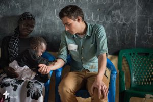 Phil Jaseph, a GEO missionary in Kenya serving as the communications specialist for the Africa region, plays with an infant during a Mercy Medical Team clinic Tuesday, June 10, 2014, at the Luanda Doho Primary School in Kakmega County, Kenya. LCMS Communications/Erik M. Lunsford