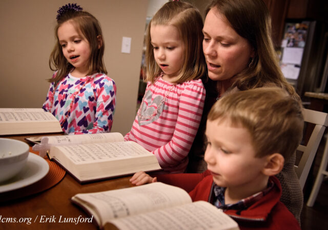 Laurie Vogt sings from the Lutheran Service Book with her children Elizabeth, Abigail (in lap) and Carl during an evening devotion with the Congregation at Prayer resource at their home on Sunday, Feb. 7, 2016, in Menomonee Falls, Wis. LCMS Communications/Erik M. Lunsford