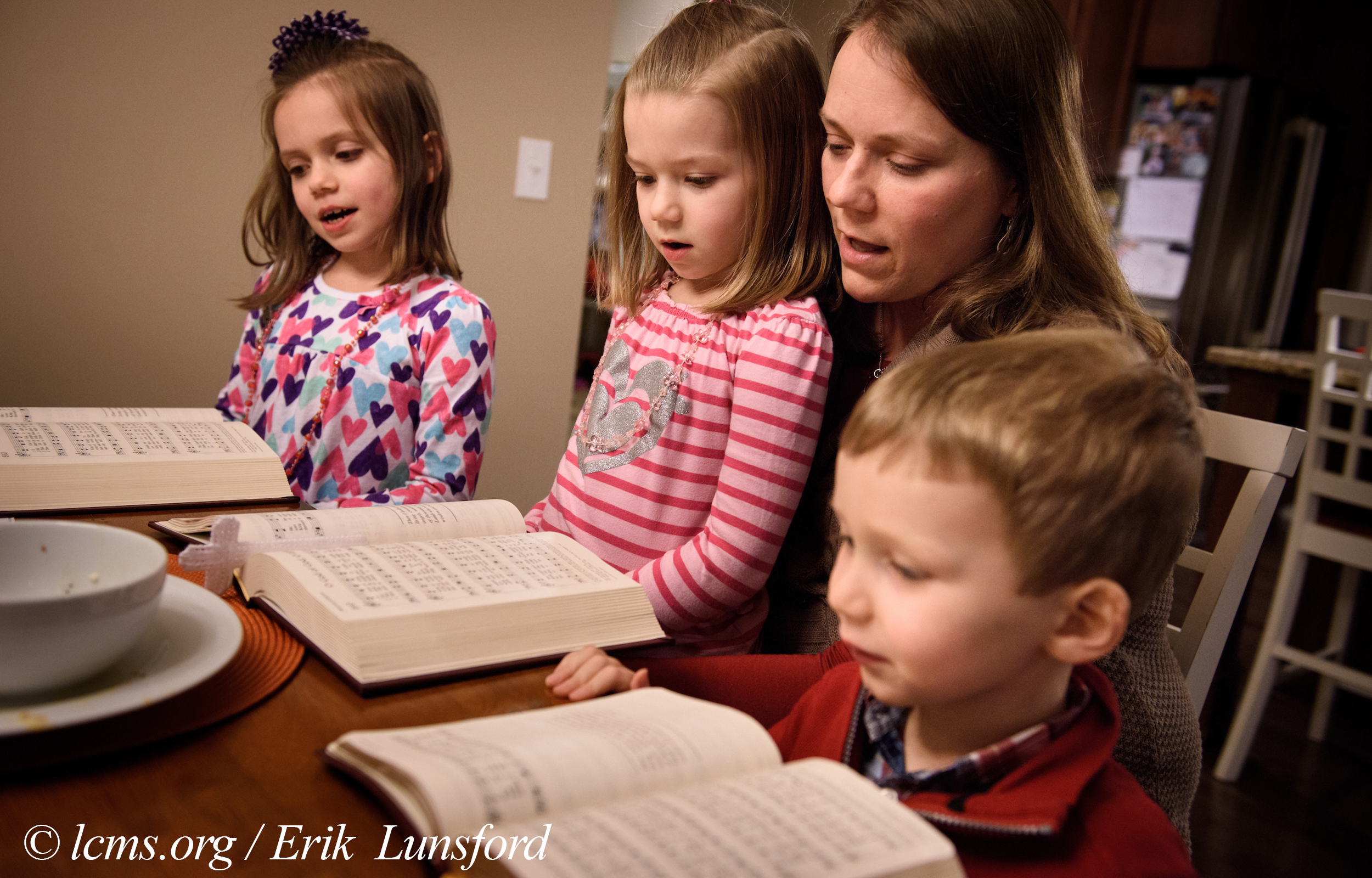 Laurie Vogt sings from the Lutheran Service Book with her children Elizabeth, Abigail (in lap) and Carl during an evening devotion with the Congregation at Prayer resource at their home on Sunday, Feb. 7, 2016, in Menomonee Falls, Wis. LCMS Communications/Erik M. Lunsford