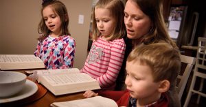 Laurie Vogt sings from the Lutheran Service Book with her children Elizabeth, Abigail (in lap) and Carl during an evening devotion with the Congregation at Prayer resource at their home on Sunday, Feb. 7, 2016, in Menomonee Falls, Wis. LCMS Communications/Erik M. Lunsford