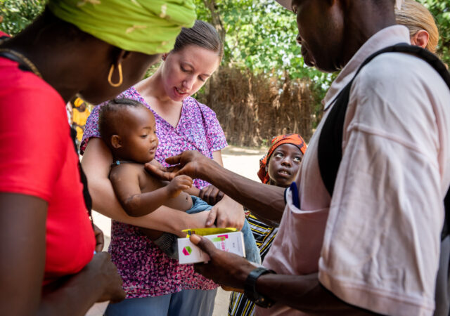 Molly Christensen, career missionary to Togo, carries a baby suffering from a very high fever on the fifth day of the LCMS Mercy Medical Team on Friday, May 11, 2018, in the Yardu village outside Koidu, Sierra Leone, West Africa. LCMS Communications/Erik M. Lunsford