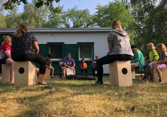 Summer Campers near Leipzig, Germany, play on new cajons (box drums) with Deaconess Kim Bueltmann. (Facebook: Deaconess in Deutschland)